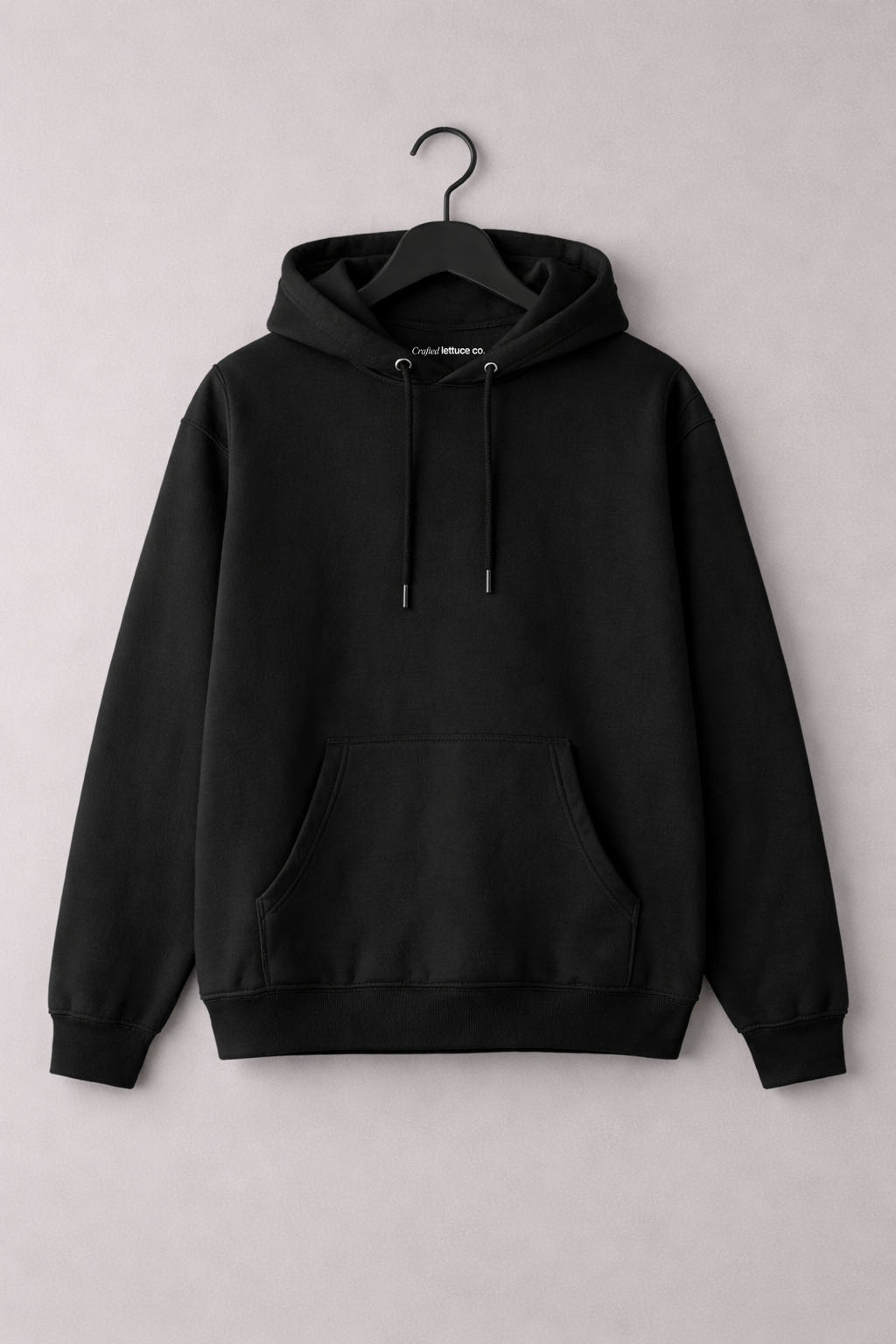 Black pullover hoodie hanging on a hanger with a front kangaroo pocket and adjustable hood