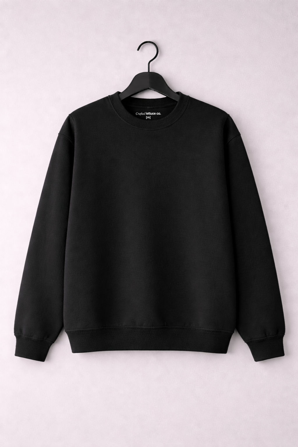 Black crewneck sweatshirt hanging on a hanger with a clean minimal background